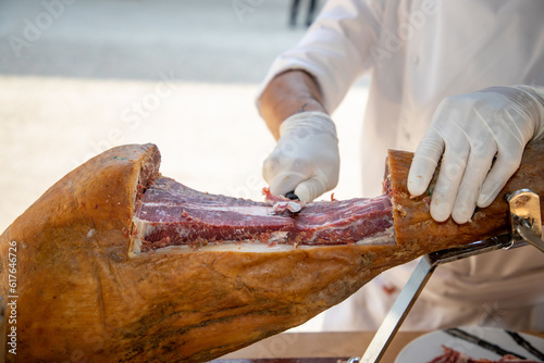 Knife cutting serrano chef man hand slicing of italian dry cured pork cured ham prosciutto photo