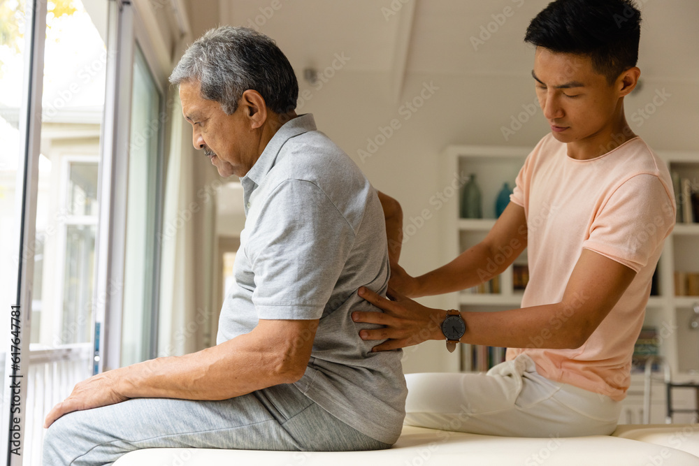 Fototapeta premium Diverse male physiotherapist and senior male patient massaging back