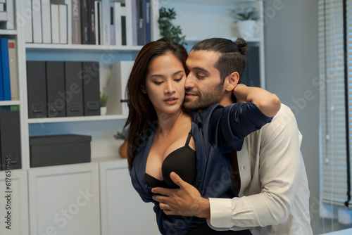 Couple having fun together at work and having sex on the desk working in the office at the company during working hours.