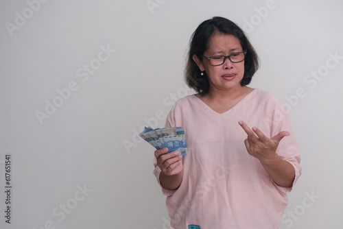 A woman holding some money in one hand while calculating something with her other hand. photo
