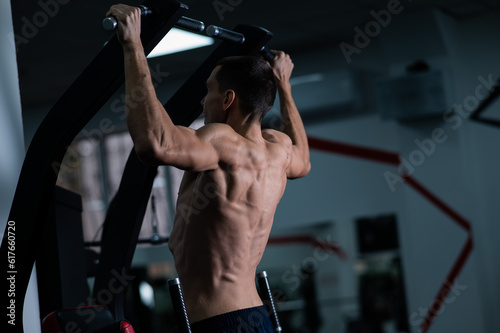 Back view of shirtless man with pull-ups in gym.  © Михаил Решетников