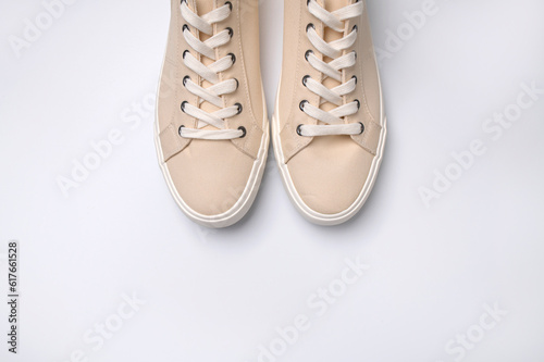 Beige fabric sneakers on white background flat lay top view. Fashion sneakers, casual sports shoes with laces. Stylish sneakers, minimalistic footwear background with copy space