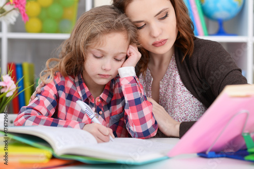 Cute little girl with her mother doing homework