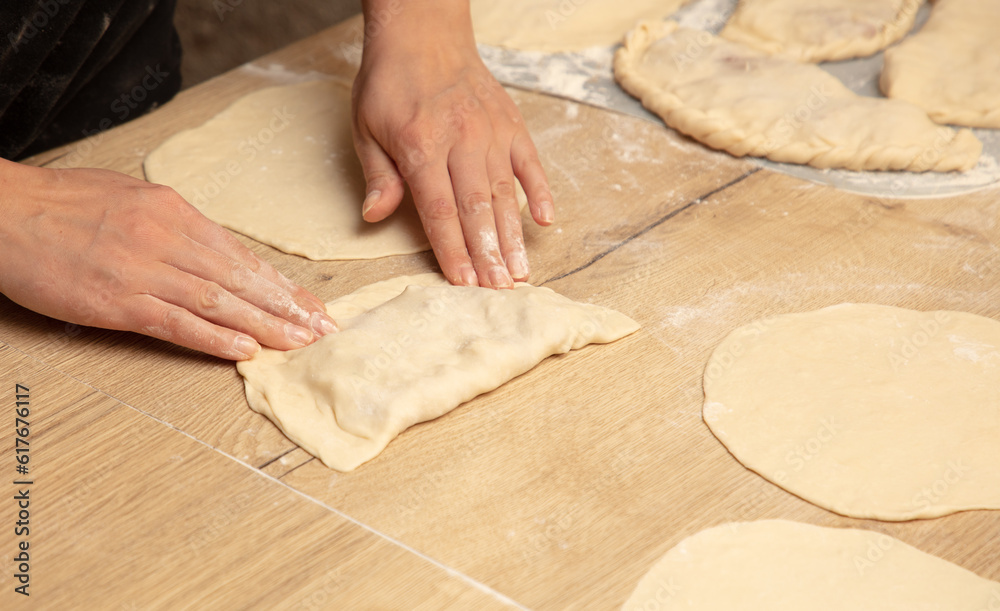 A woman prepares pies from dough and minced meat on the table A woman prepares pies from dough and minced meat on the table