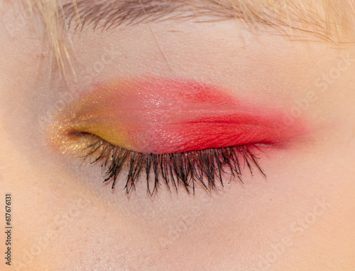 Close-up shot of beautiful woman's eye with red and yellow makeup