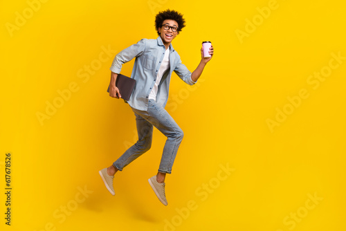 Full body profile photo of crazy guy jump run hurry hold netbook coffee isolated on yellow color background