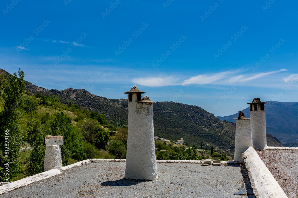 Roofs with beautiful old hand-built whitewashed chimneys and scenery mountain views in the background. Capileira, Andalusia, Spain