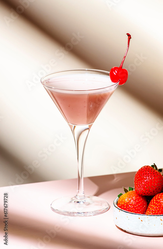 Bounty martini summer cocktail drink with vodka, liqueur, cream, strawberries and ice in glass with red cocktail cherry. Beige pink background
