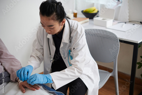 Doctor inserting IV catheter to deliver medication or fluids to patient photo