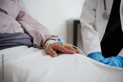 Sick senior woman sitting in bed with catheter in hand photo