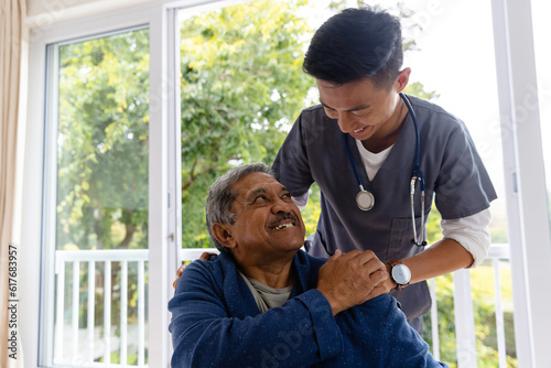 Cuadro en lienzo Happy diverse male doctor discussing with senior male patient in wheelchair at h