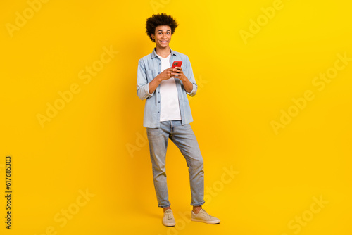 Full size portrait of handsome man hold use smart phone chatting isolated on yellow color background