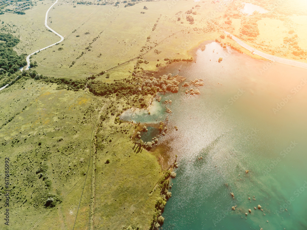 Aerial view on mountain lake. Drone over water reservoir at mountain valley covered with green spring forest. Beautiful view from above on smooth blue surface of mountain lake among highlands. Nobody