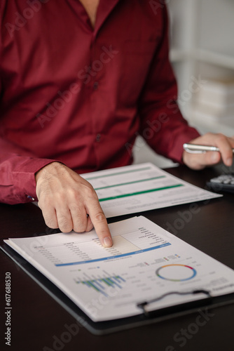 Business man pointing to a pie chart document showing company financial information, He sits in her private office, a document showing company financial information in chart form. Financial concepts.