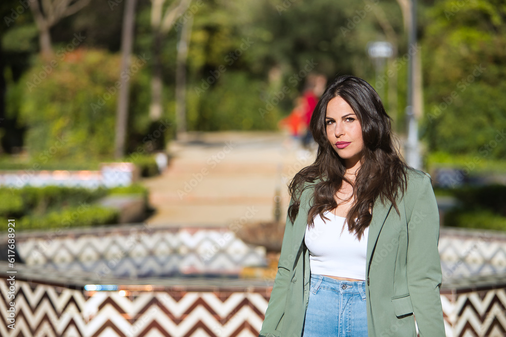 Young and beautiful woman, Hispanic, brown hair, with green jacket and jeans, looking at the camera serious and relaxed. Concept beauty, fashion, seriousness, relax. Young and beautiful woman, Hispanic, brown hair, with green jacket and jeans, looking at the camera serious and relaxed. Concept beauty, fashion, seriousness, relax.