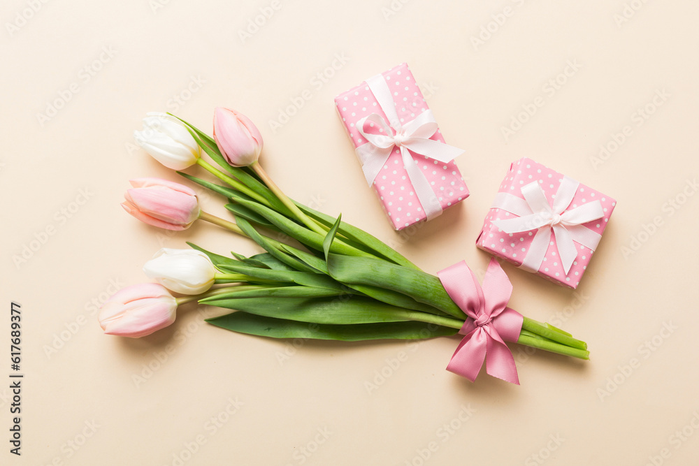Pink tulips flowers and gift or present box on colored table background. Mothers Day, Birthday, Womens Day, celebration concept. Space for text top view Pink tulips flowers and gift or present box on colored table background. Mothers Day, Birthday, Womens Day, celebration concept. Space for text top view