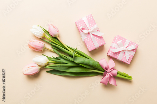 Pink tulips flowers and gift or present box on colored table background. Mothers Day  Birthday  Womens Day  celebration concept. Space for text top view