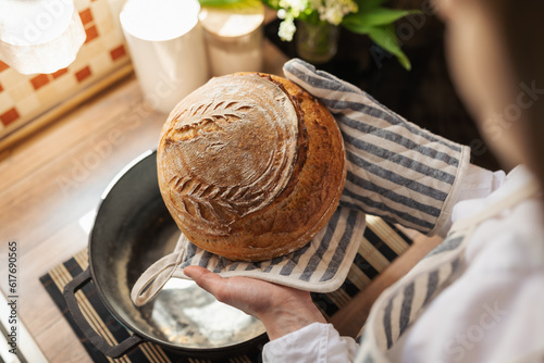 Hostess taking just baked bread from a pot. Tasty aromatic bread self made at home photo