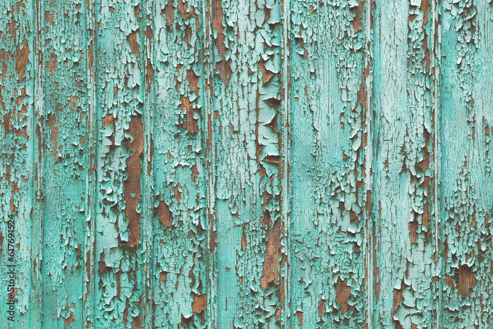 Background formed by a wall of wooden boards on which the remnants of old green paint. Peeled green paint on a wooden surface as a background, texture, pattern.
