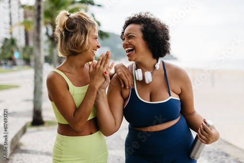 Fitness women laughing and high-fiving after a beach workout