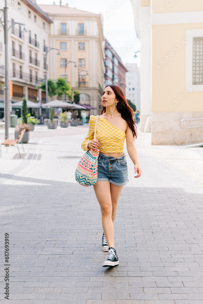 Woman in summer clothes walking looking up outdoors