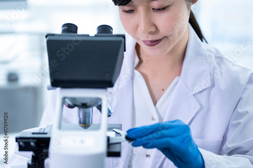A female scientist conducting research under a microscope 