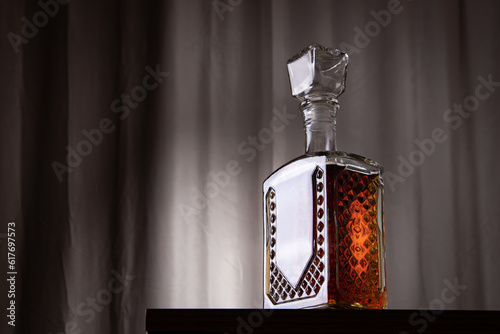 decanter bottle of whiskey or rum with ice on the table with a black dark background with free space for text