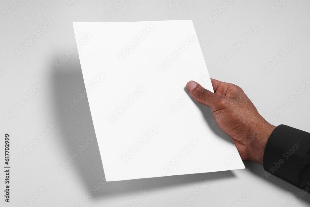 African American man holding sheet of paper on white background, closeup. Mockup for design African American man holding sheet of paper on white background, closeup. Mockup for design
