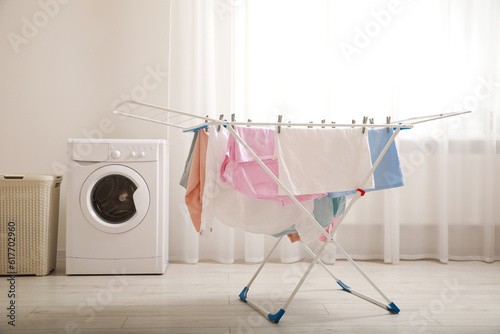 Clean laundry hanging on drying rack indoors