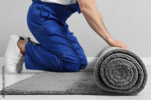 Worker unrolling new carpet on floor in room, closeup