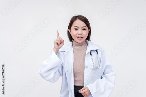 Portrait of a young and skilled doctor, medical student, intern posing while pointing upwards. Isolated on a white background.