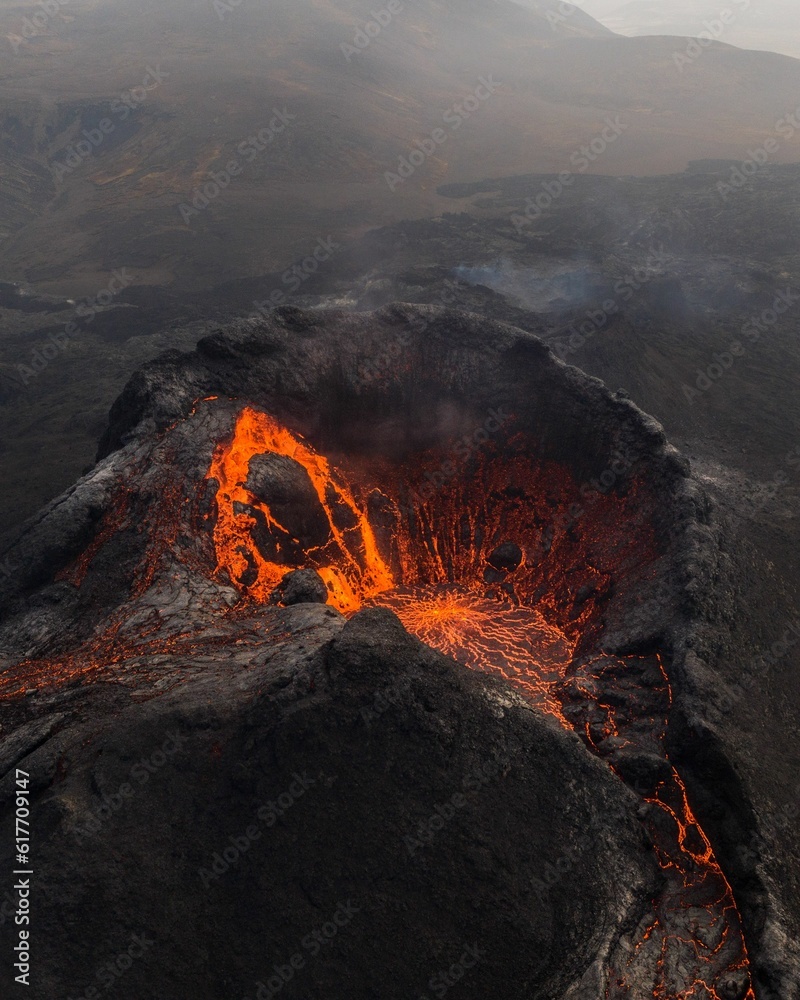 View of Fagradalsfjall volcano crater in Iceland, with a vibrant orange hue emitting from the lava - obrazy, fototapety, plakaty 
