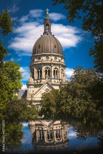 Vertical shot of The Christuskirche reflecting on a pond in Mainz, Germany photo