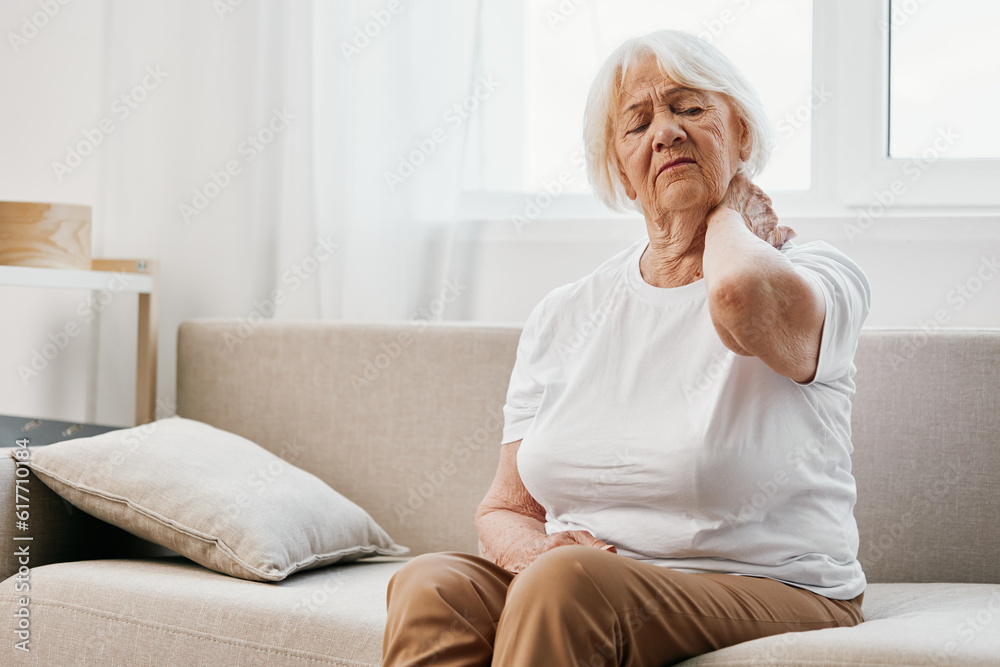 Elderly woman severe neck pain sitting on the sofa, health problems in old age, poor quality of life. Elderly woman severe neck pain sitting on the sofa, health problems in old age, poor quality of life.