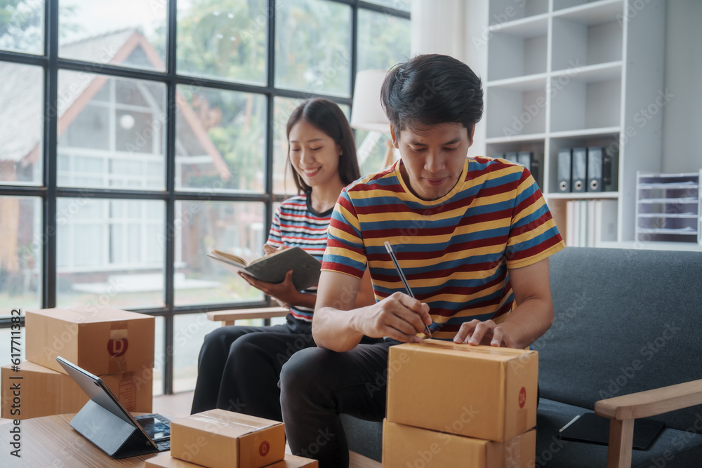 Two chinese couple startup small business owner packing goods for delivery to clients. Freelancer SME man and woman selling online product on social media application and short reel video. Two chinese couple startup small business owner packing goods for delivery to clients. Freelancer SME man and woman selling online product on social media application and short reel video.