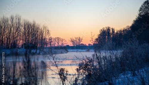 the setting sun shines over a frozen lake and forest