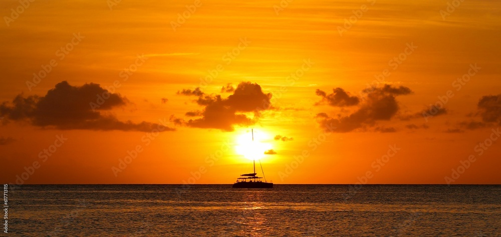 an orange sunset reflecting in the water with a small boat