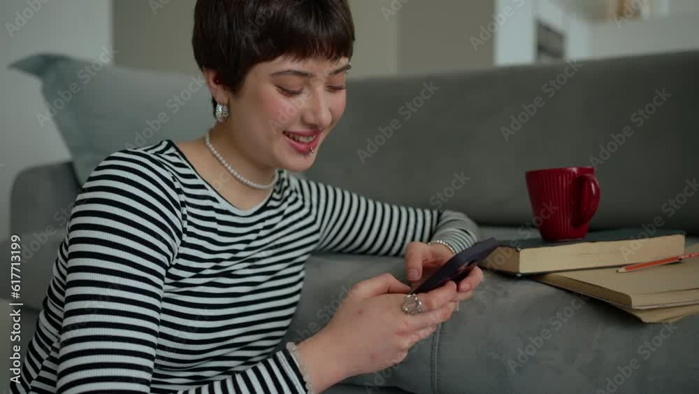 Positive young woman with piercings texting on mobile at home Positive young woman with piercings texting on mobile at home