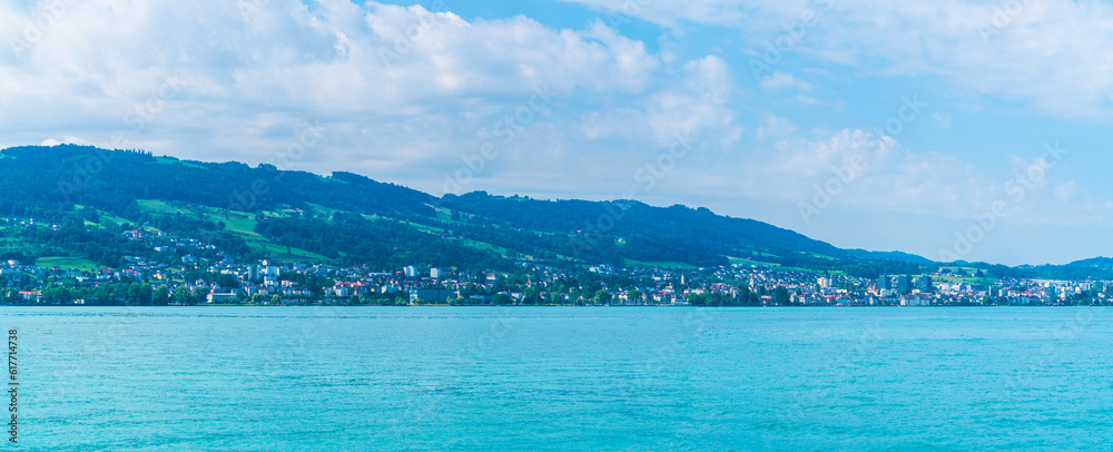 Switzerland, XXL panorama view to rohrschach city houses buildings from lakeside at bodensee lake constance water view with sun
