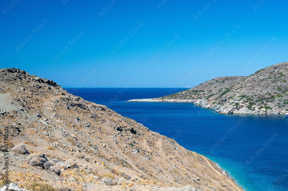 Picturesque landscape featuring a grassy hill rising above the serene waters, Kythnos island, Greece
