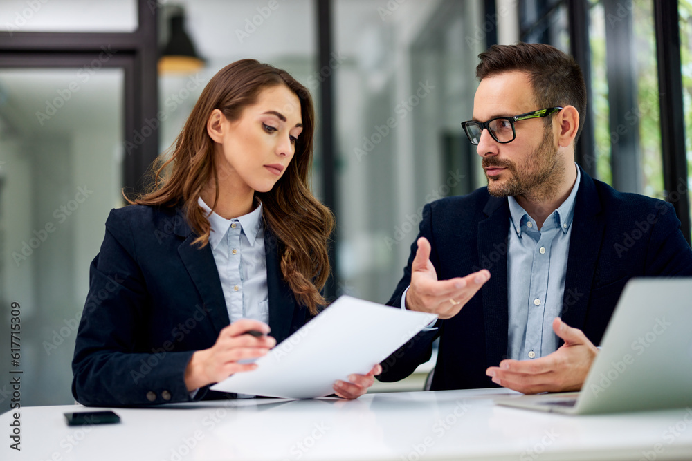 A businesswoman reading documents and talking with a male colleague at the office. A businesswoman reading documents and talking with a male colleague at the office.