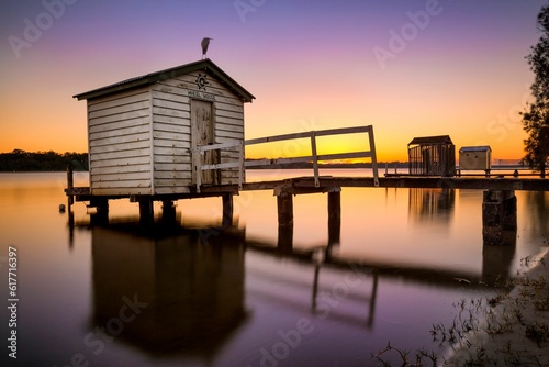 a boat dock and shack are in the water at sunset
