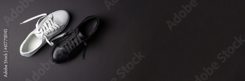 White and black leather shoes on a black background. sneakers with laces. New shoes. Horizontal image. Banner for insertion into site.