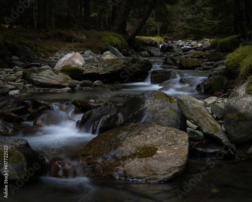 Landscape of a stream with long exposure in a forest covered in rocks