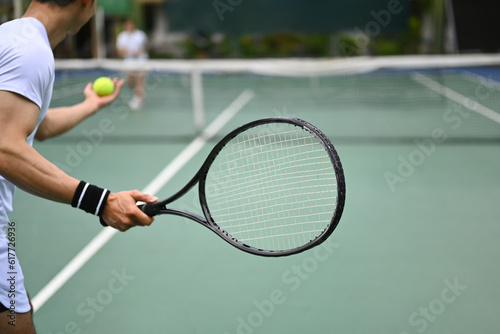 Tennis player serving tennis ball during a match on open court. Sport, fitness, training and active life concept © Prathankarnpap