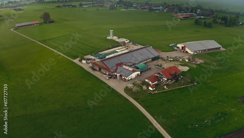 Aerial of a green valley and a cattle farm with solar panels in a small village