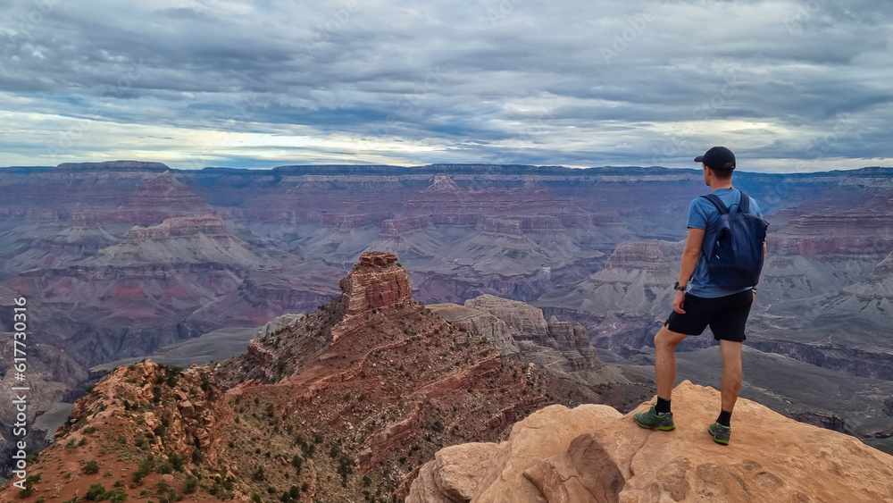 Man with scenic view from Ooh Ahh point on South Kaibab hiking trail at South Rim, Grand Canyon National Park, Arizona, USA. Colorado River weaving through valleys and rugged terrain. O Neill Butte