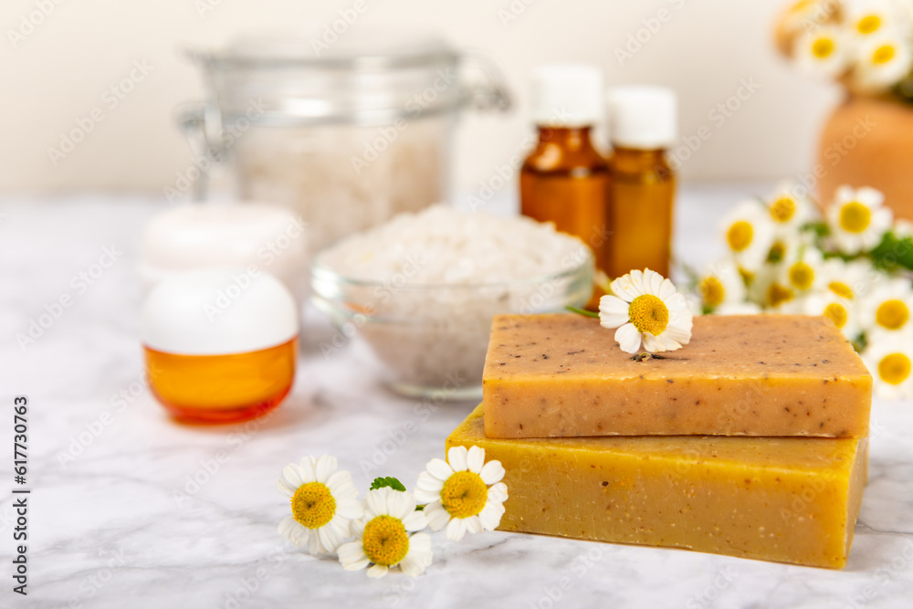 Chamomile Spa. Essential oil, sea salt, chamomile flowers, body cream and handmade soap. Natural herbal cosmetics with chamomile flowers on a textured background.Beauty concept. Cosmetic tube. 