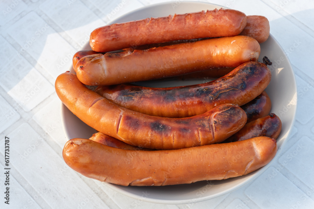 Grilled sausages are being prepared outdoors on a warm sunny day, picnic Grilled sausages are being prepared outdoors on a warm sunny day, picnic