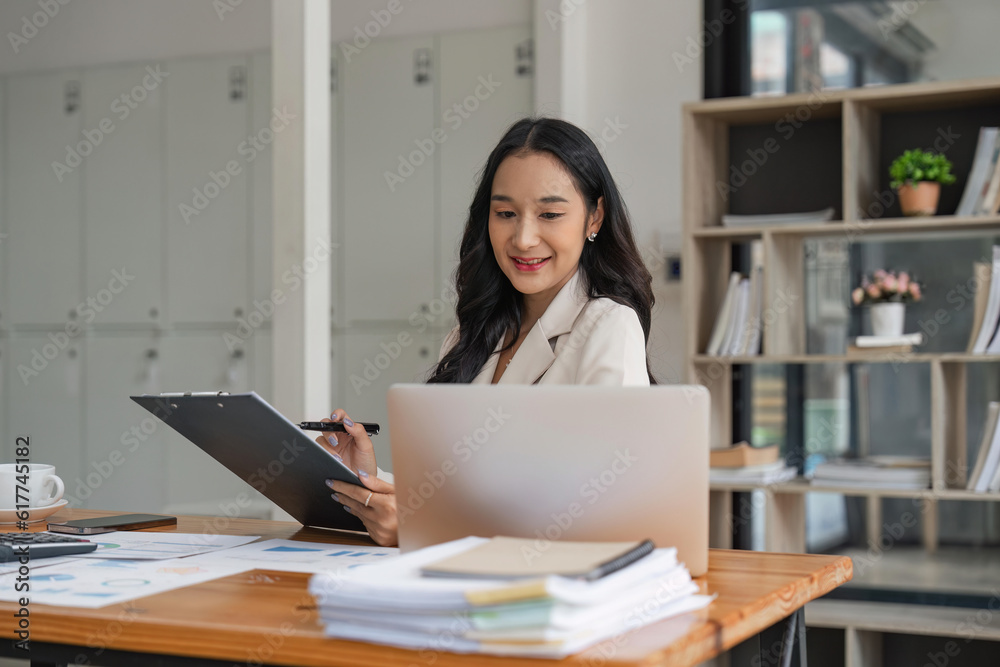 Asian businesswoman working for financial graphs showing results about their investments, planning successful business growth process by laptop computer